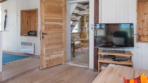 Un intérieur en bois avec un téléviseur, une porte en bois et un coin repas.