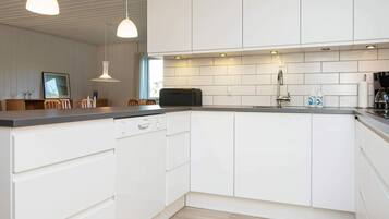 A modern kitchen with white cabinets, a dishwasher, a sink, and pendant lighting.