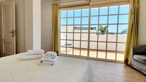A hotel room with a large bed, a balcony with a view, and a door. - Bright and airy spacious three bedroom Holiday Home with private pool (La Caleta)