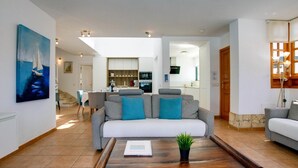 A spacious living area with a grey sofa, a wooden coffee table, and a painting of a sailboat on the wall. - Bright and airy spacious three bedroom Holiday Home with private pool (La Caleta)