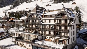 A multi-story hotel with a glass pool, surrounded by snow-covered hills and traditional architecture. - Luxury Apartment, Panoramic Mountain Views, 5 Star Spa Facilities - 3 Bedroom (Chateau-d'Oex)