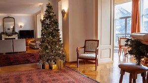 A cozy living room with a large Christmas tree, a fireplace, and a view of mountains through the window. - Luxury Apartment, Panoramic Mountain Views, 5 Star Spa Facilities - 3 Bedroom (Chateau-d'Oex)