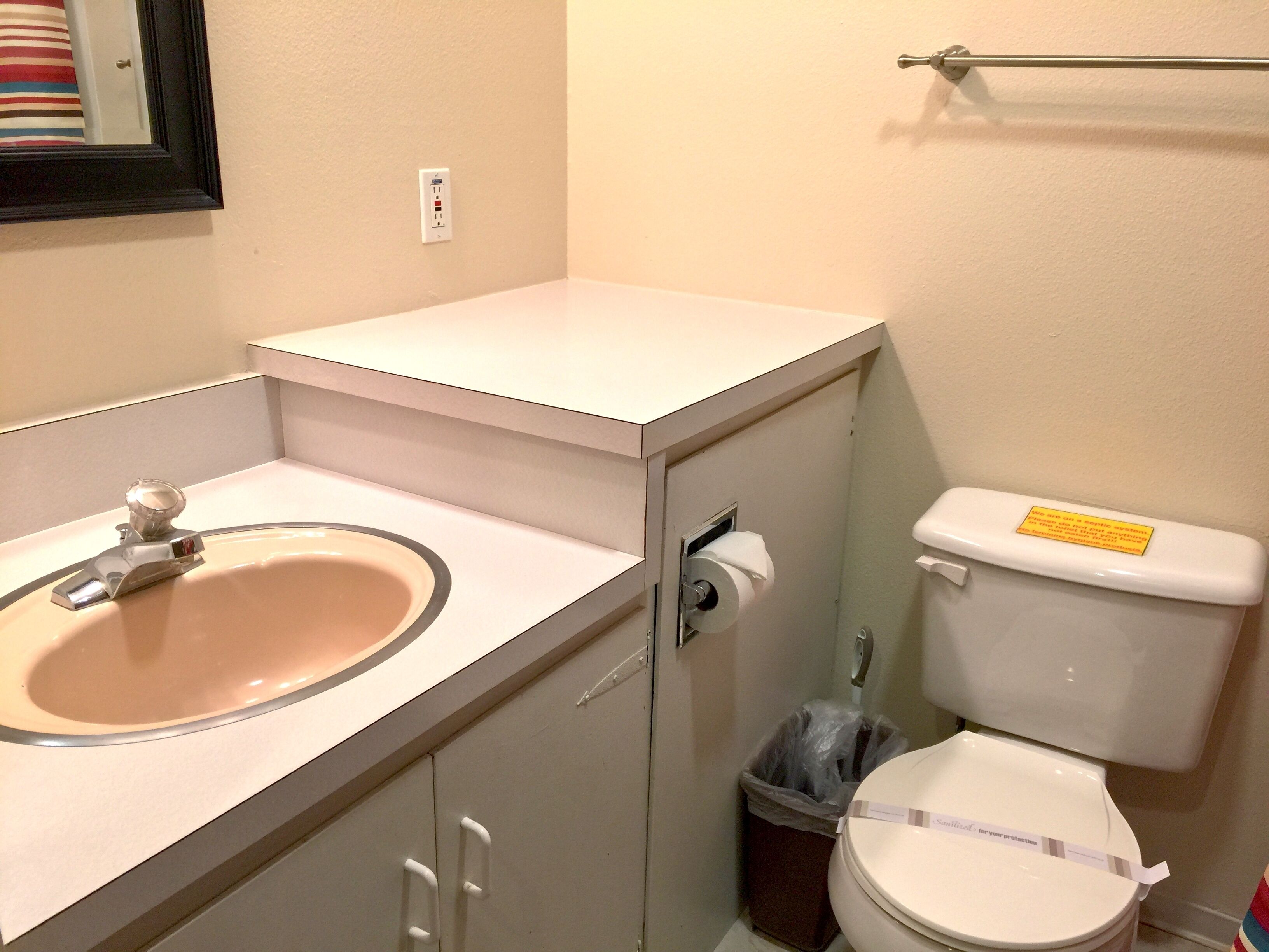 A small bathroom with a sink, toilet, and a trash can.