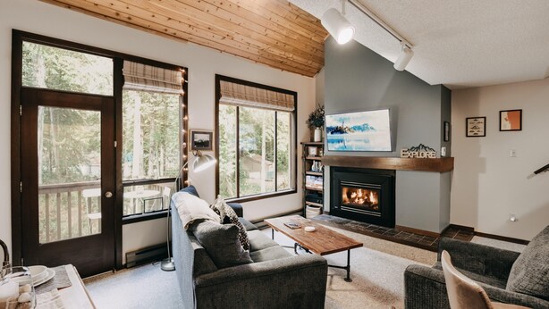 A cozy living room with a fireplace, large windows, and a television. - Condo - Pets OK - Fireplace, Sleeps 4! (Deming)