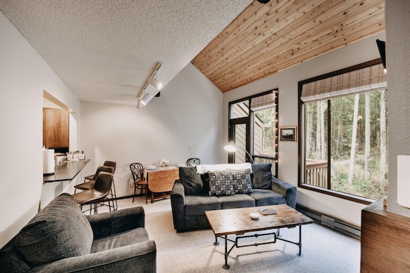 A cozy living room with a sofa, coffee table, and dining area.
