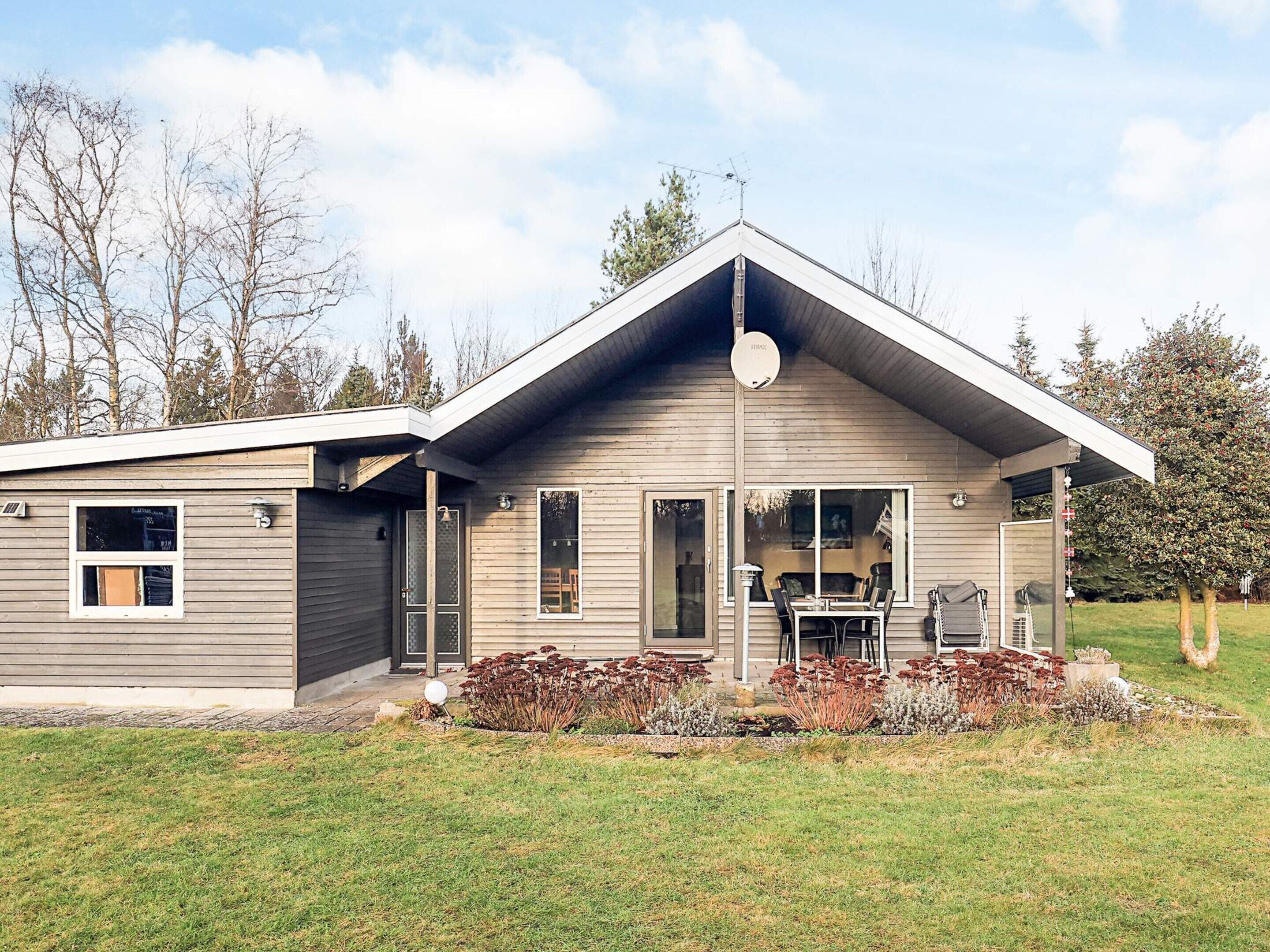 A two-story house with a sloped roof, a satellite dish, and a covered patio area with outdoor furniture.