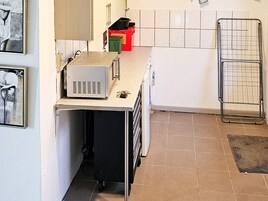 Una cocina con mostrador, microondas, pileta y un tendedero.