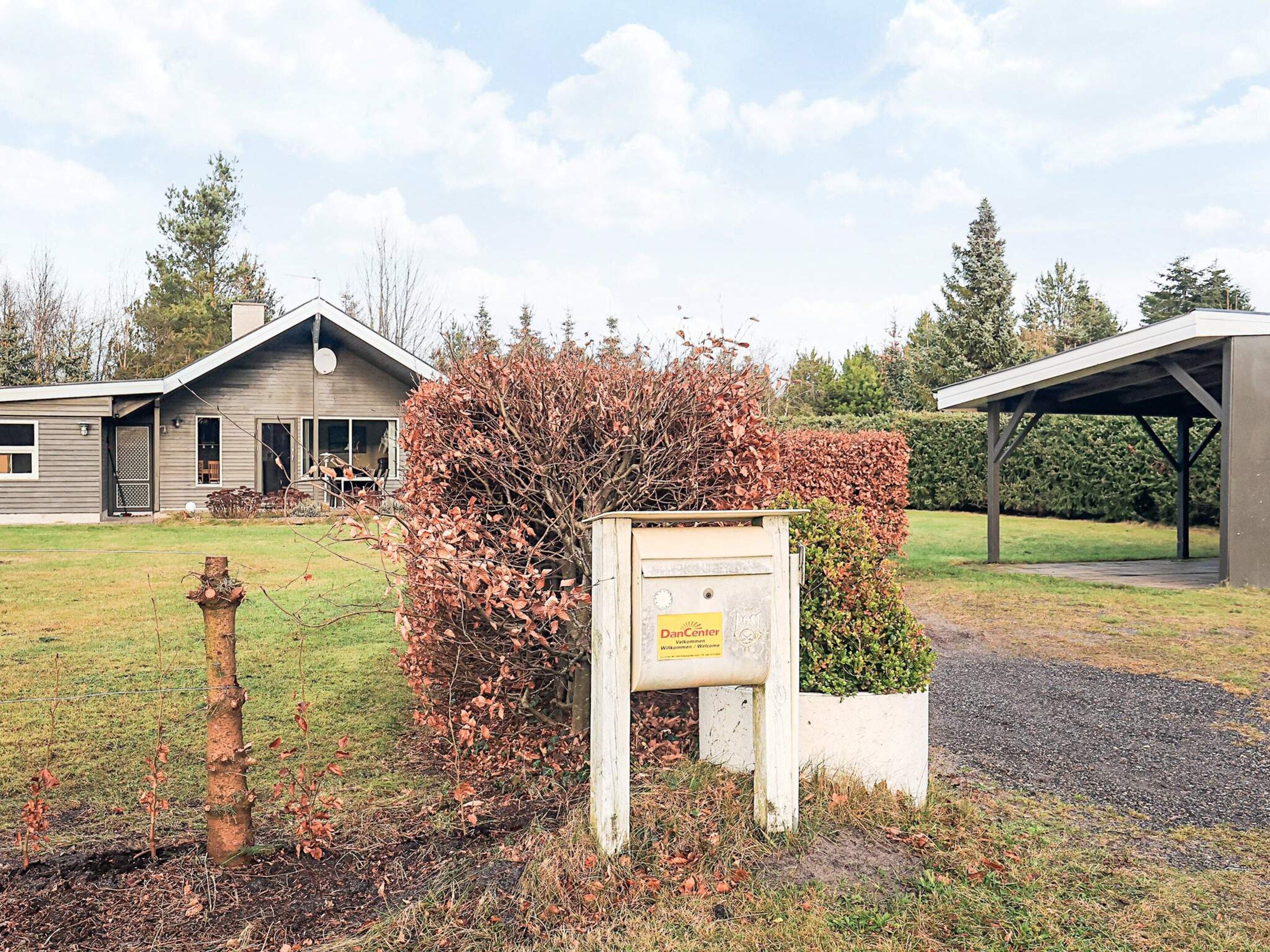 A residential property with a wooden house, a covered outdoor area, and a mailbox.