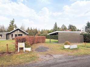 En boligejendom med hus, carport og velholdt græsplæne.