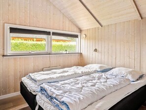 Une pièce avec un lit, une fenêtre et des murs en bois.