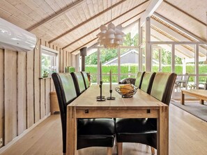 A dining area with a long wooden table, black leather chairs, and a modern pendant light. - 5 Star Holiday Home in Juelsminde (Horsens)