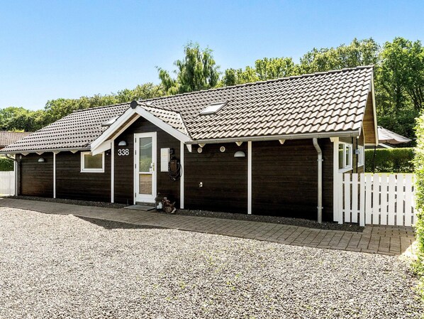A wooden building with a numbered door, a gravel driveway, and a white picket fence.