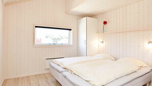 Una camera da letto con un letto, una finestra, uno scaffale a parete con un vaso e un lampadario.