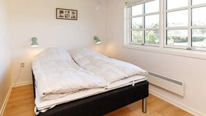 Un dormitorio con cama, dos lámparas de pared, una ventana con vistas y un radiador.