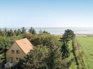 A yellow house with a red roof, surrounded by trees and a grassy field, overlooking a body of water. - 4 Star Holiday Home in Romo (Rømø)