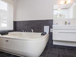 A modern bathroom with a freestanding bathtub, a white vanity with drawers, and a dark tiled backsplash. - 4 Star Holiday Home in Romo (Rømø)