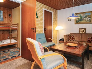 Une pièce chaleureuse avec un lit superposé, une table en bois, un canapé et une lampe.