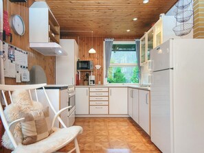 A compact kitchen with wooden cabinetry, a microwave, a coffee maker, and a window with curtains. - Cozy Holiday Home in Jutland near Lake (Silkeborg)