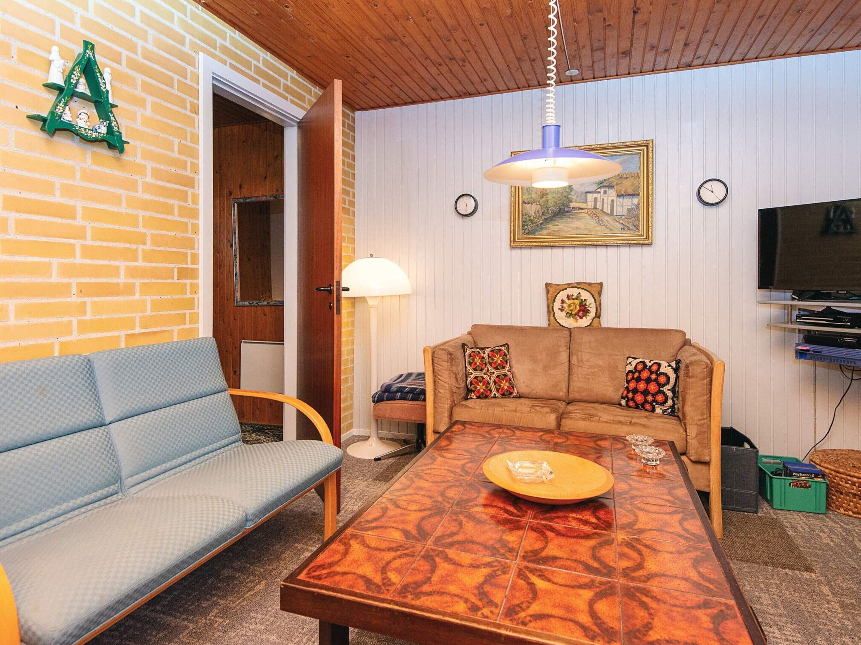 Un salon confortable avec un canapé, une table basse, une lampe, un tableau et un téléviseur.