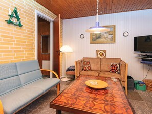 A cozy living room with a sofa, a coffee table, a lamp, a painting, and a television. - Cozy Holiday Home in Jutland near Lake (Silkeborg)