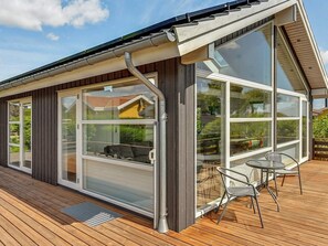 A modern house with large windows, a wooden deck, and a sliding glass door. - 4 Person Holiday Home in Hejls (Hejls)