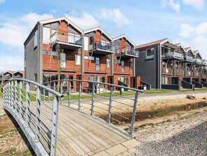 A modern multi-story residential building with balconies, a wooden deck, and a metal railing. - 4 Person Holiday Home in Bogense-by Traum (Bogense)