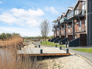 A modern residential building with multiple balconies and a wooden deck area.