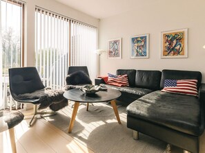 A modern living room with a sofa, chairs, and artwork on the wall.