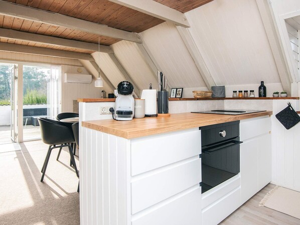 A modern kitchen with a wooden countertop, white cabinetry, and a built-in oven.
