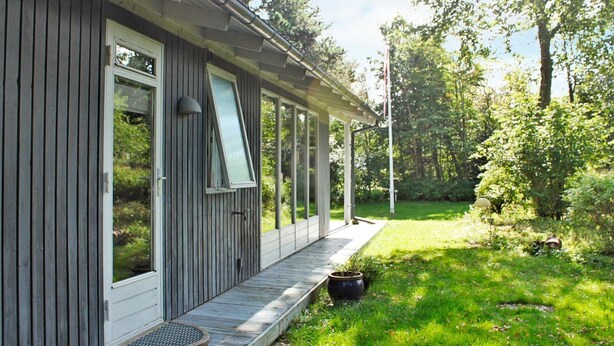 Una casa de madera con un porche, ventanas amplias y una chimenea.