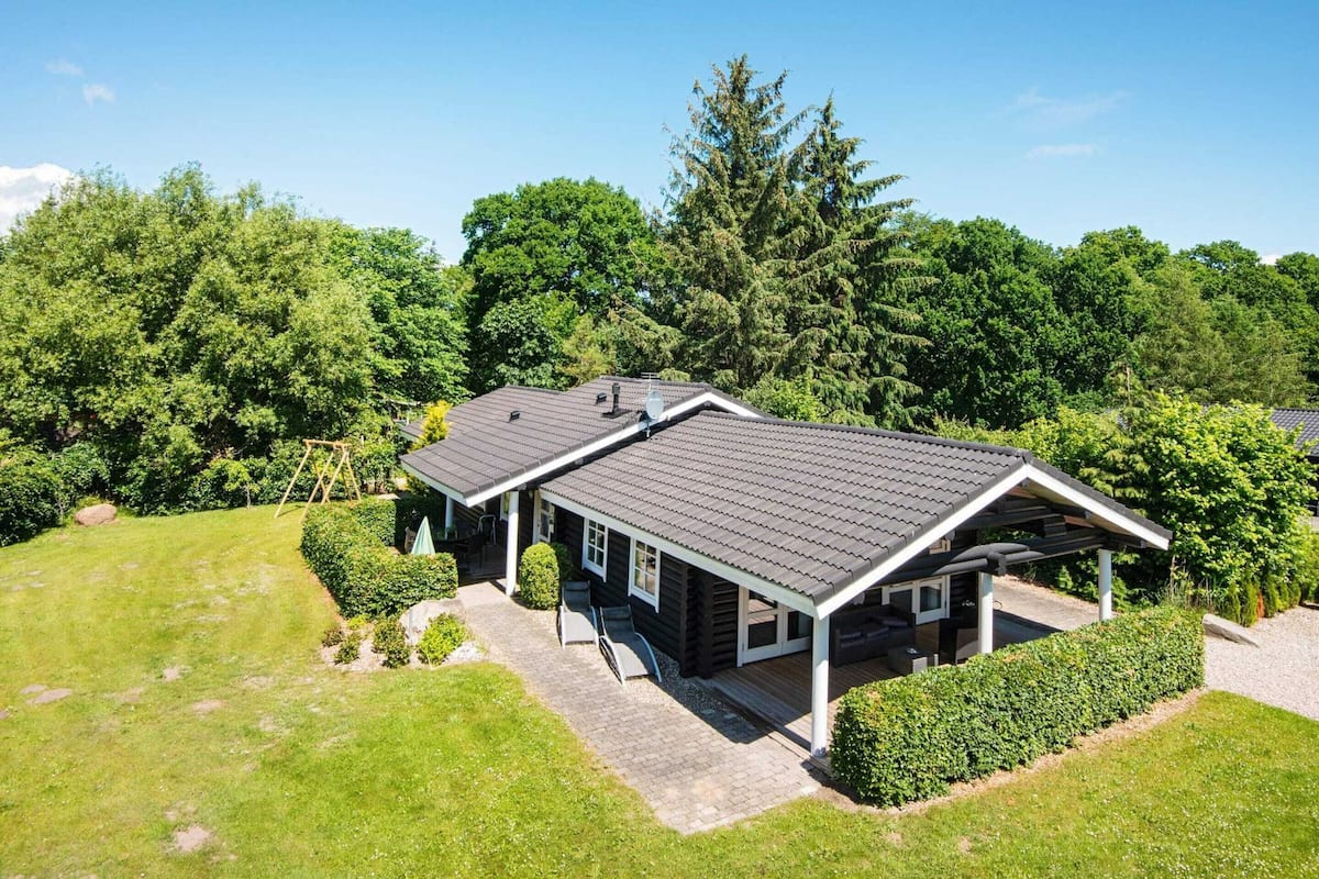 A two-story log cabin with a covered porch and a landscaped yard.
