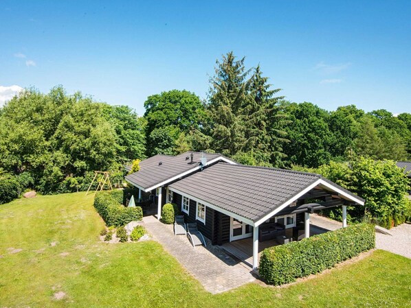 A two-story log cabin with a covered porch and a landscaped yard.