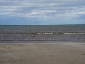 A beach with a sandy shore and calm sea under a cloudy sky. - 6 Person Holiday Home in Blokhus (Blokhus)