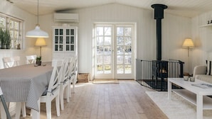 A room with a dining table, chairs, a fireplace, and a sofa. - 6 Person Holiday Home in Blokhus (Blokhus)