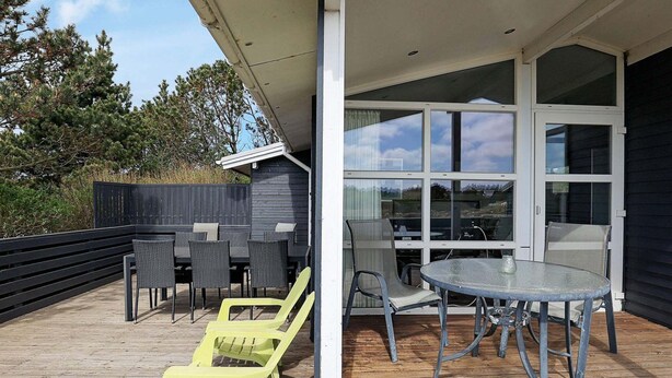 Eine Terrasse im Freien mit Tisch und Stühlen, ein Holzdeck und Blick auf die Umgebung.