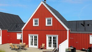 A red barn with a sloped roof, white trim, and a door with glass panels.