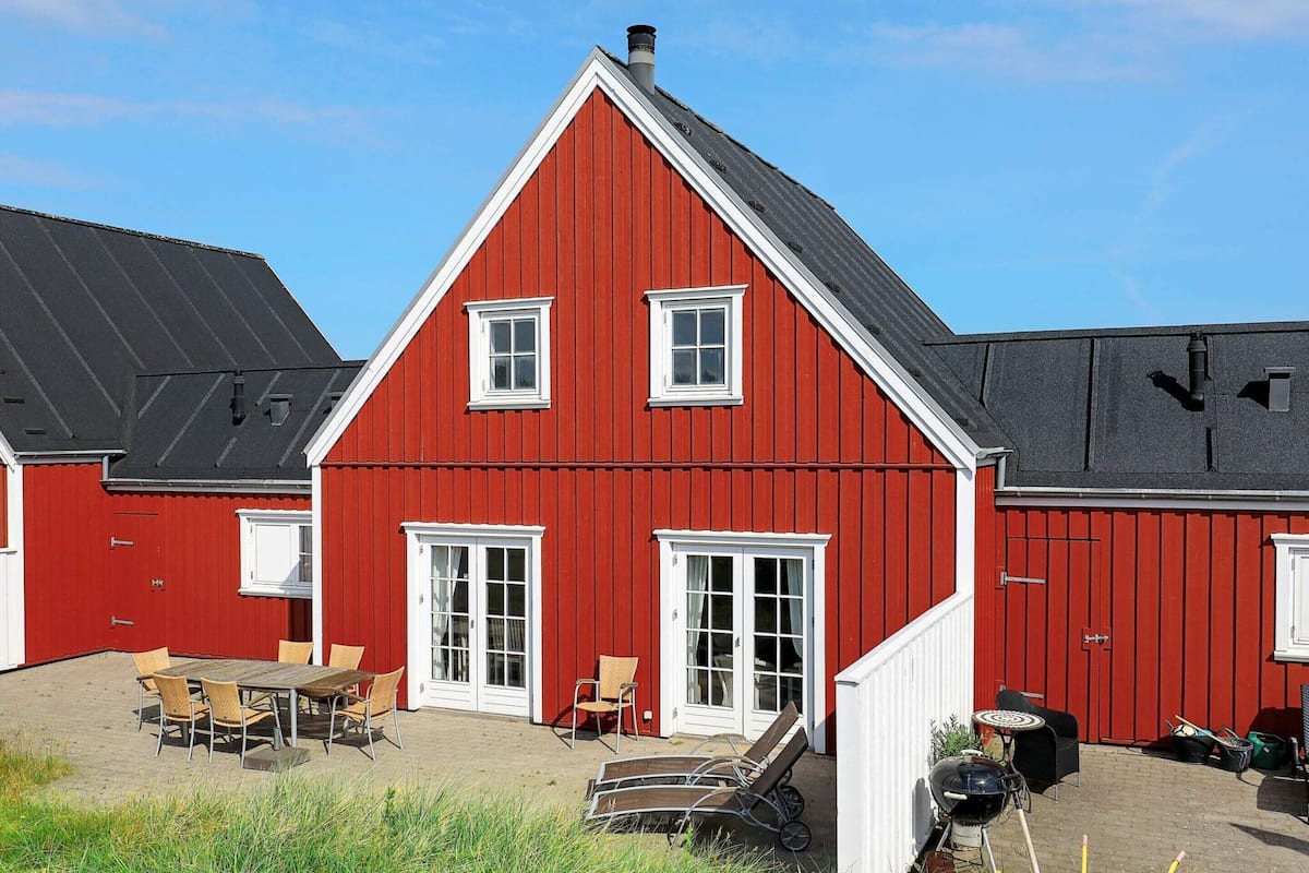 A red barn with a sloped roof, white trim, and a door with glass panels.
