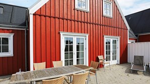 A red building with a patio area featuring a table and chairs. - 5 Star Holiday Home in Blokhus (Blokhus)