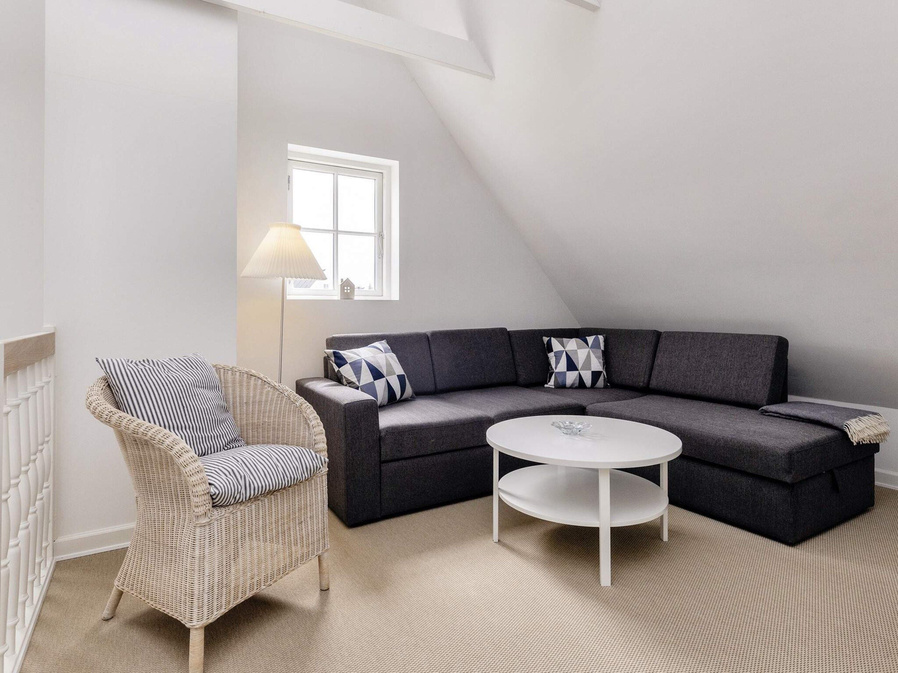 A modern living room with a sectional sofa, a wicker chair, a round coffee table, and a floor lamp.