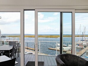 A balcony with a view of a marina, a table, and chairs. - Holiday Home in Wendtorf (Schönberg)