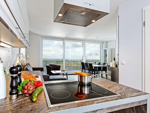 A modern kitchen with a built-in stove, large windows, and a dining area with a view.