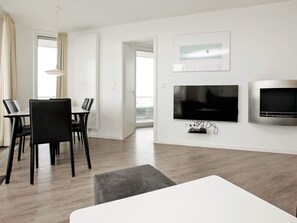 A modern living room with a flat-screen TV, a fireplace, and a dining area with chairs.