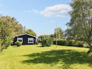A single-story house with a dark exterior, a visible number '23' on the side, and a well-maintained lawn.
