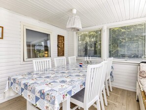 A dining area with a table set for six, white chairs, and a patterned tablecloth.
