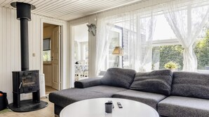 Ein gemütliches Wohnzimmer mit einer Couch, einem weißen Couchtisch und einem Kaminofen.