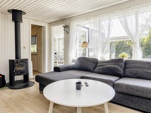 A cozy living room with a sofa, a white coffee table, and a black wood-burning stove. - 7 Person Holiday Home in Hals (Hals)