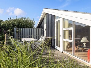 A modern house with a patio area, a dining table, and outdoor seating. - 5 Star Holiday Home in Lokken (Lokken)