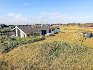 A row of cabins with a grassy field in the foreground and a clear sky. - 5 Star Holiday Home in Lokken (Lokken)