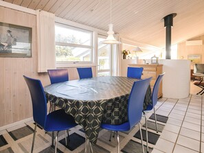 A dining area with a round table, blue chairs, and a patterned tablecloth. - 5 Star Holiday Home in Lokken (Lokken)