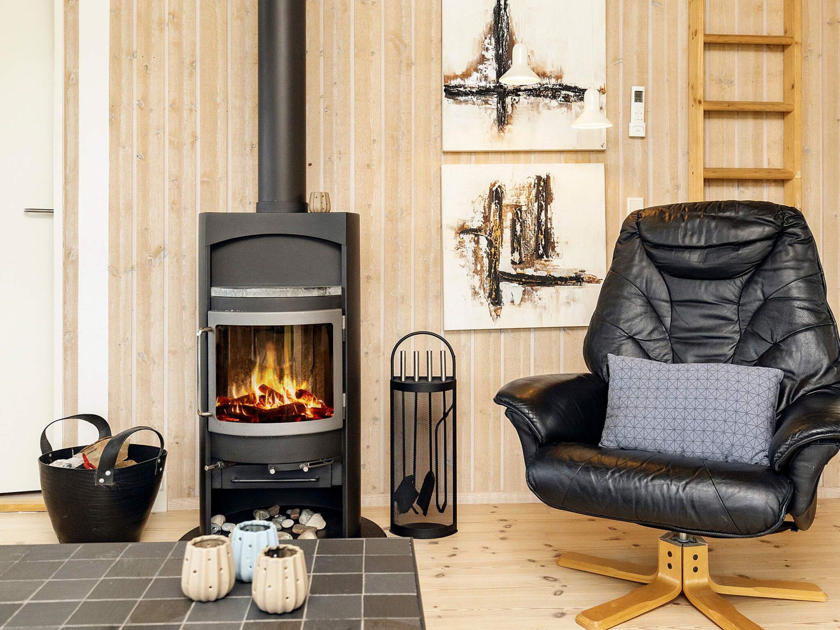 Een gezellige kamer met een moderne haard, een comfortabele leren fauteuil en een houten vloer.